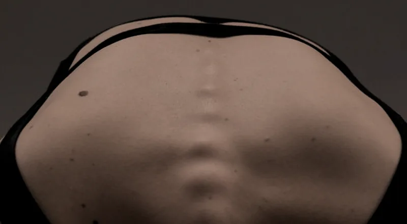 Close das costas de uma pessoa, com a coluna e as escápulas em evidência.