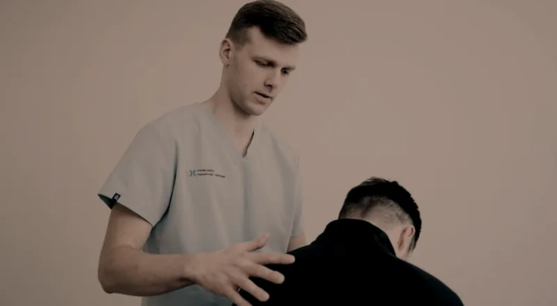 Profissional de saúde apoiando as mãos nas costas de uma pessoa curvada para frente.